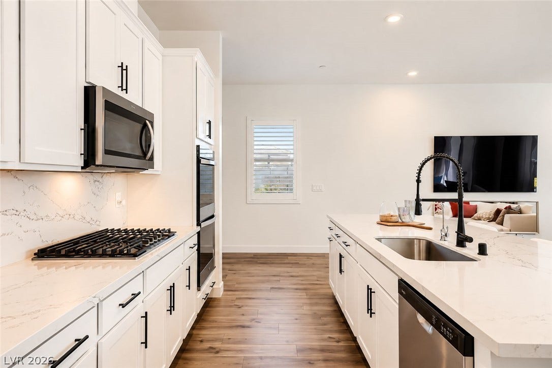 An open kitchen connects seamlessly with the living area over rich wood-style flooring.