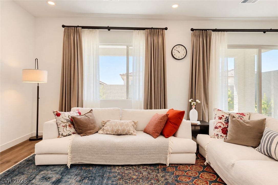 Sunlight streams through large windows onto rich wood flooring in this inviting space.