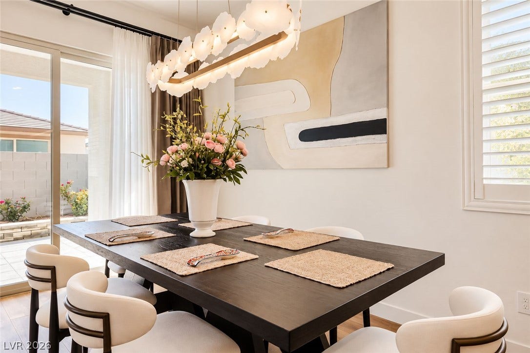 Natural light streams through large glass doors in this elegant dining area with wood flooring.