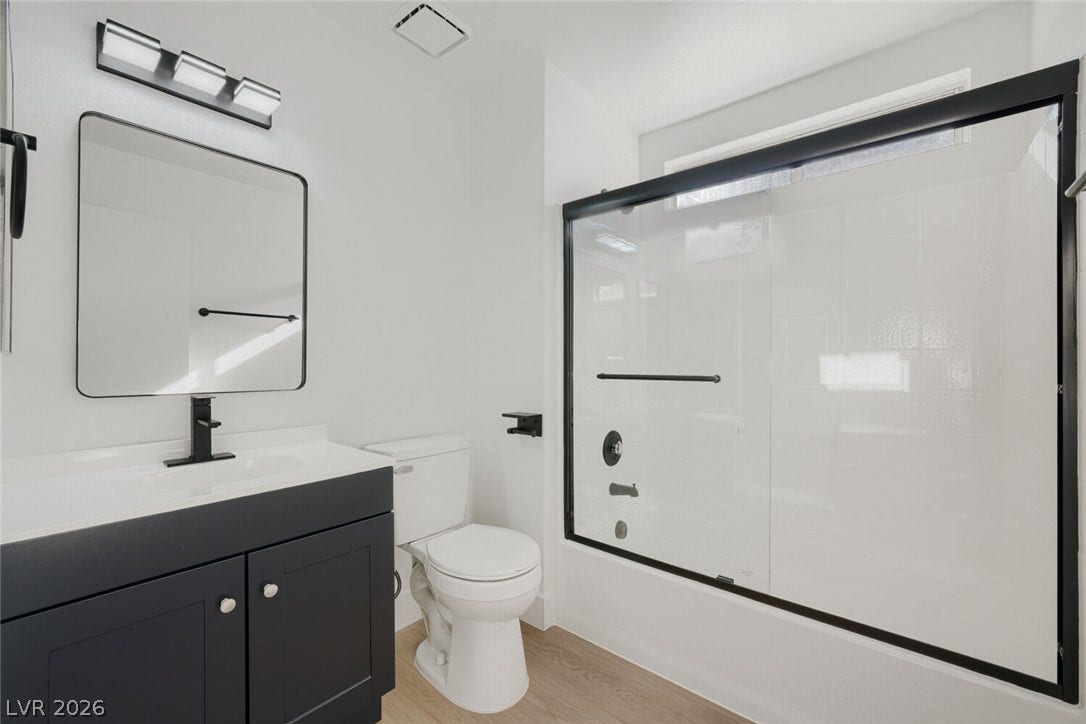 5736 Baffy Circle, Las Vegas, NV 89142 A modern bathroom features a dark vanity, sleek black hardware, and a glass-enclosed tub.
