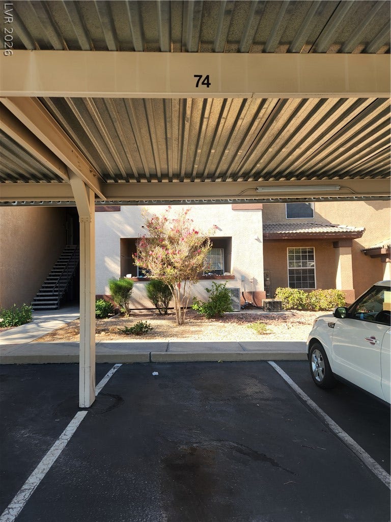 231 W Horizon Ridge Parkway, #924, Henderson, NV 89012 An asphalt driveway runs alongside a sheltered parking area next to stucco residential units.