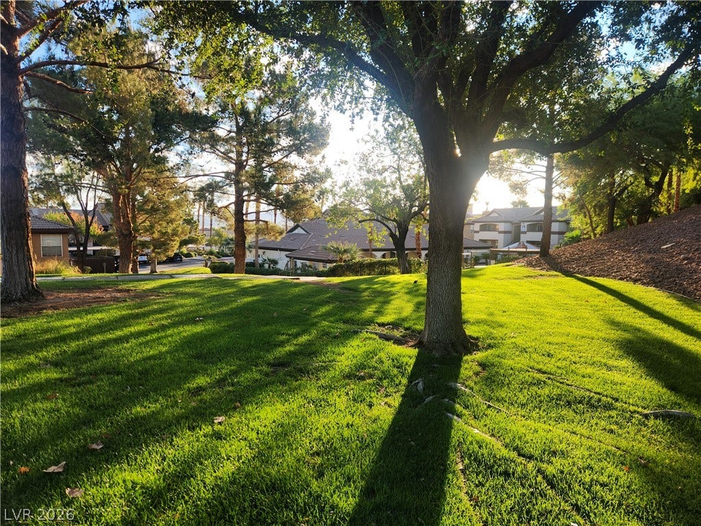 231 W Horizon Ridge Parkway, #924, Henderson, NV 89012 Mature trees shade a manicured grassy slope under filtered sunlight.