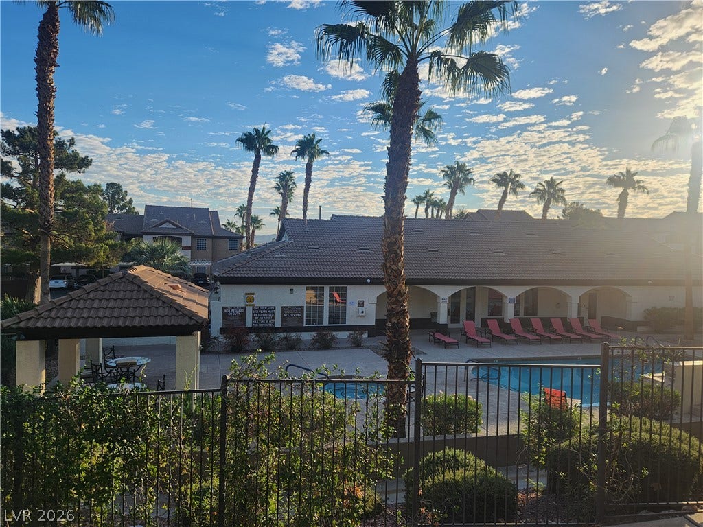 231 W Horizon Ridge Parkway, #924, Henderson, NV 89012 Mature palms and lush plantings surround a gated community pool under a wide desert sky.