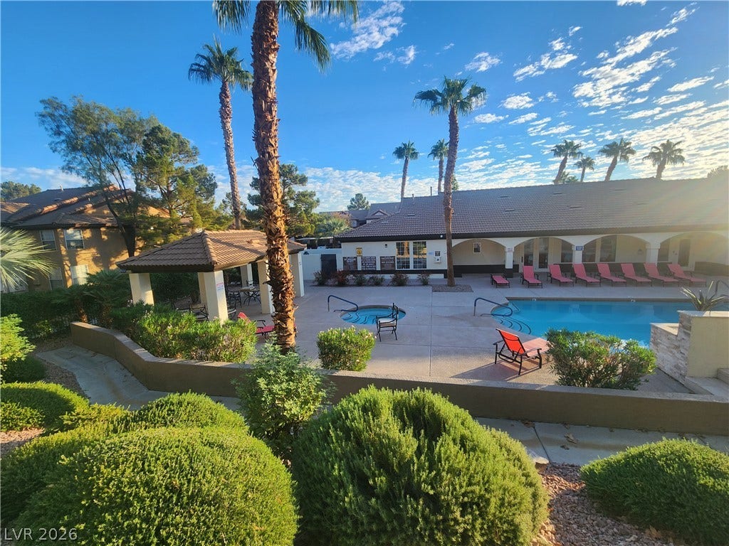 231 W Horizon Ridge Parkway, #924, Henderson, NV 89012 Manicured hedges frame a sparkling community pool area beneath soaring palm trees and sunny skies.