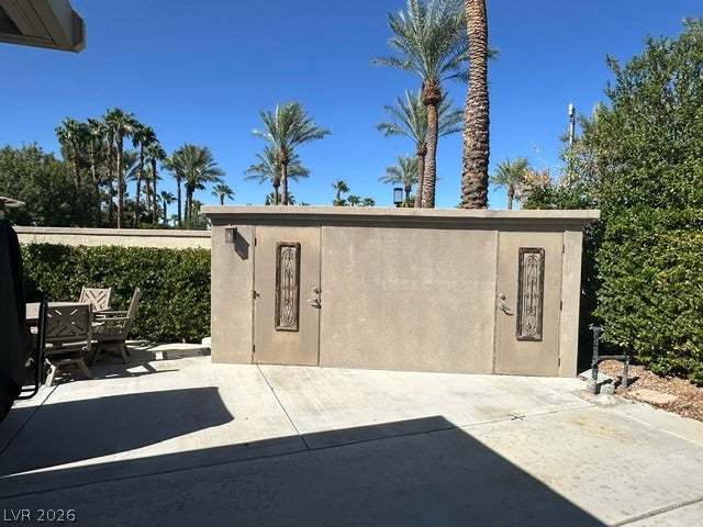 8175 Arville Street, #163, Las Vegas, NV 89139 A detached stucco storage structure stands alongside a spacious concrete patio lined with mature palm trees.