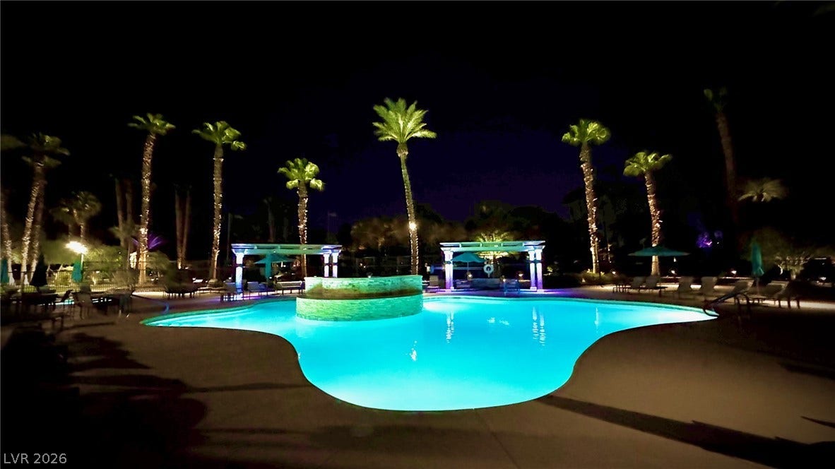 8175 Arville Street, #163, Las Vegas, NV 89139 Dramatic night lighting illuminates a resort-style swimming pool surrounded by towering palm trees.