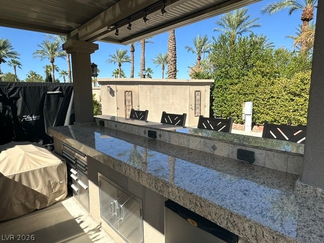 8175 Arville Street, #163, Las Vegas, NV 89139 Polished granite counters elevate this covered outdoor kitchen set against a backdrop of mature palms.