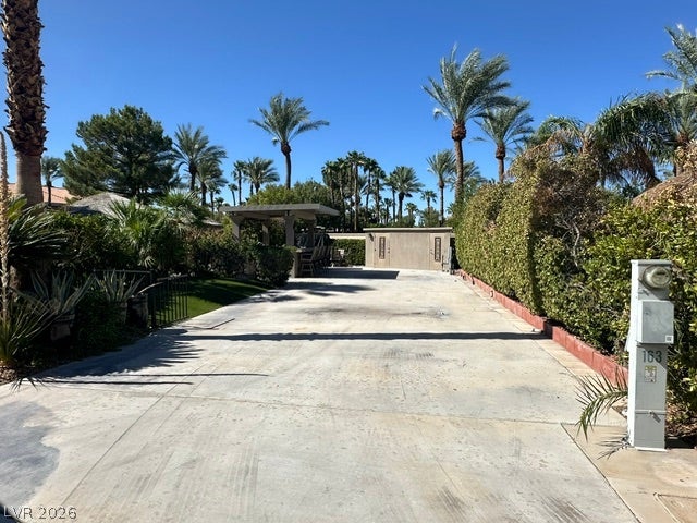 8175 Arville Street, #163, Las Vegas, NV 89139 Lush tropical landscaping and mature palm trees border a spacious concrete driveway under sunny skies.