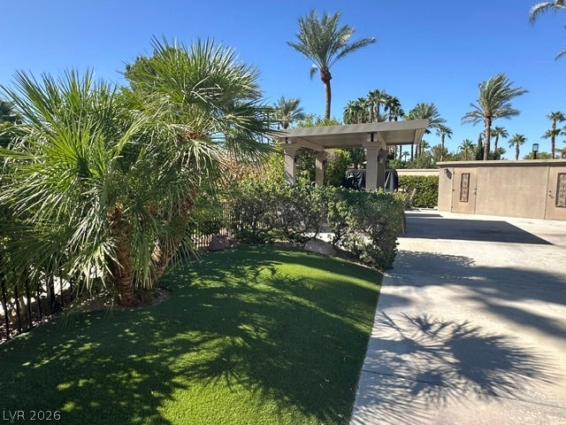 8175 Arville Street, #163, Las Vegas, NV 89139 Lush landscaping and towering palms frame a covered outdoor patio under clear blue skies.