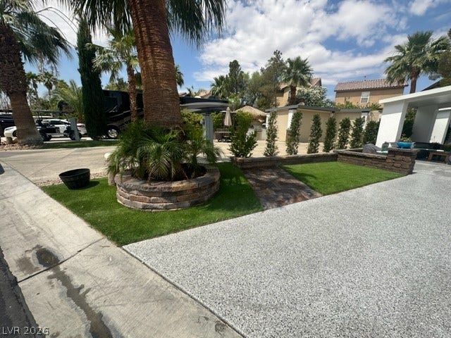 8175 Arville Street, #236, Las Vegas, NV 89139 Lush palm trees and manicured green spaces frame the paved driveway and aggregate concrete paths.