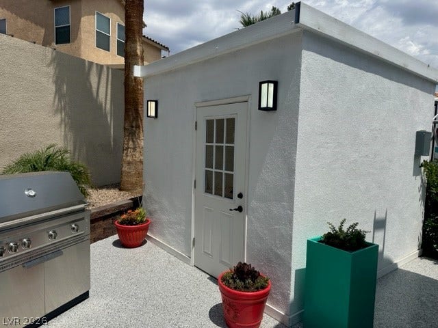 8175 Arville Street, #236, Las Vegas, NV 89139 A detached stucco structure stands adjacent to a modern outdoor grilling station on the patio.