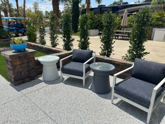 8175 Arville Street, #236, Las Vegas, NV 89139 A textured concrete patio features a built-in stone retaining wall bordered by manicured hedges.