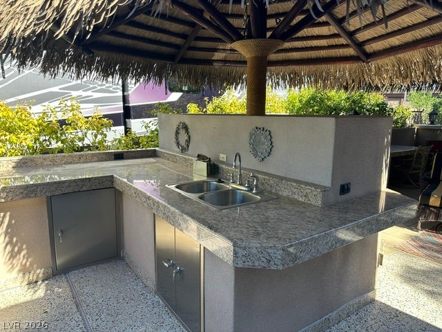 8175 Arville Street, #266, Las Vegas, NV 89139 Polished granite counters and a built-in sink define this outdoor kitchen setup under a thatched roof.