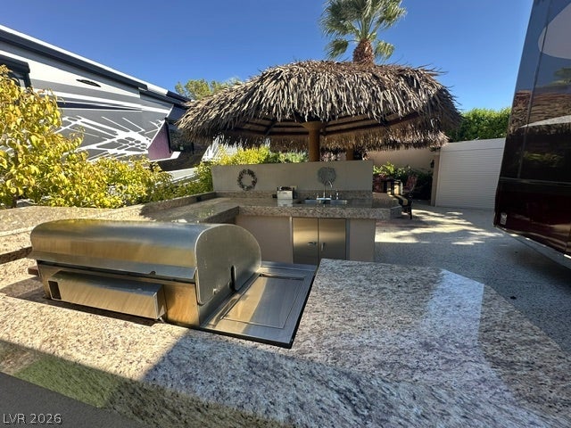 8175 Arville Street, #266, Las Vegas, NV 89139 Granite counters wrap around this built-in outdoor kitchen with a thatched umbrella.