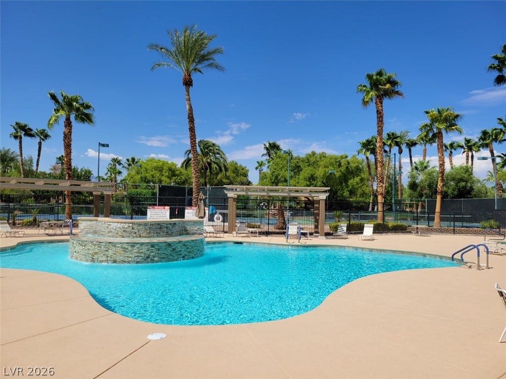 8175 Arville Street, #266, Las Vegas, NV 89139 A sparkling resort-style pool is bordered by towering palm trees under clear blue skies.