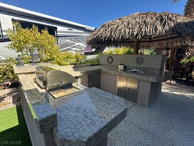 8175 Arville Street, #266, Las Vegas, NV 89139 A fully equipped outdoor kitchen with granite countertops sits beneath a tropical palapa.