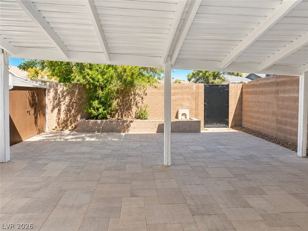 A spacious covered patio features extensive paver flooring and is enclosed by block walls.