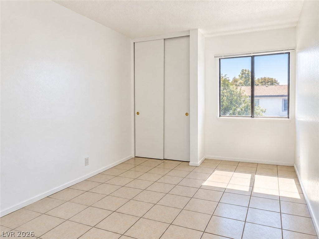 Tiled flooring and a sliding-door closet define this versatile room illuminated by natural light.