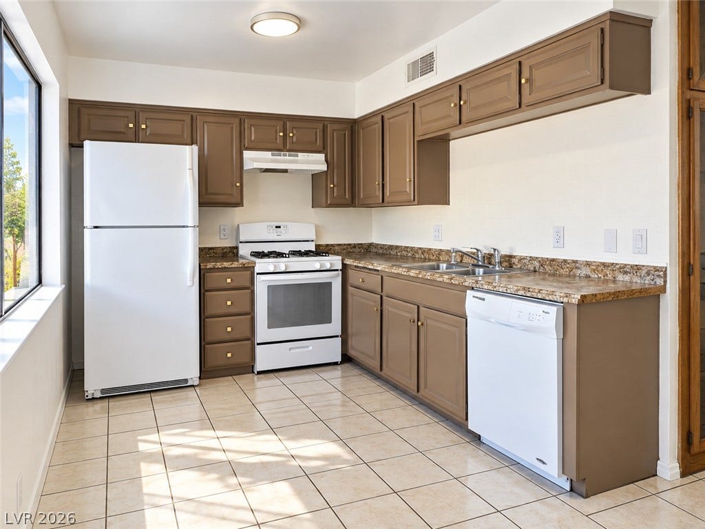A spacious kitchen highlights classic tiled flooring and abundant solid cabinetry alongside stone counters.