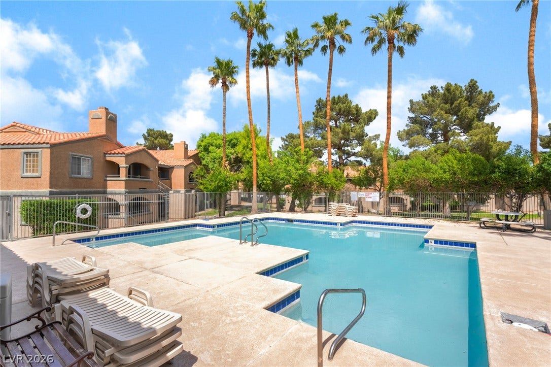 230 Mission Catalina Lane, #202, Las Vegas, NV 89107 Mature palms frame a sparkling community pool lined with concrete decking.