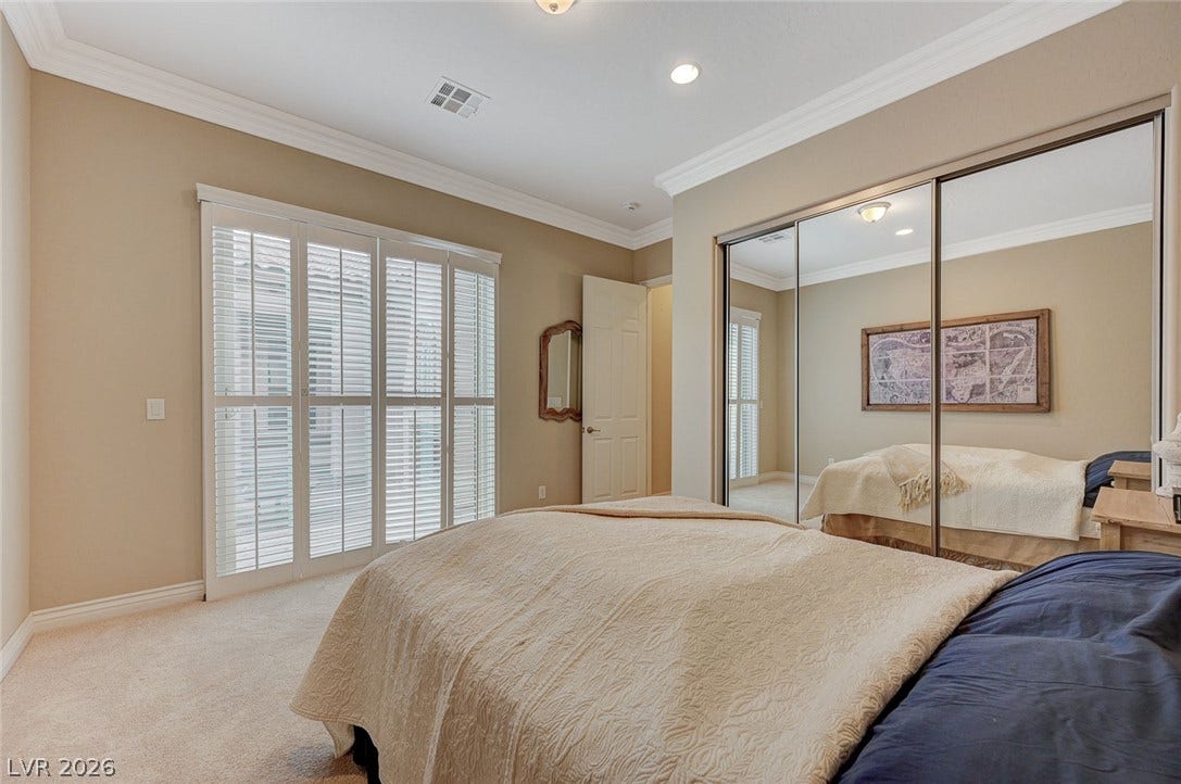 Crown molding highlights the high ceilings of this inviting bedroom with mirrored closets.
