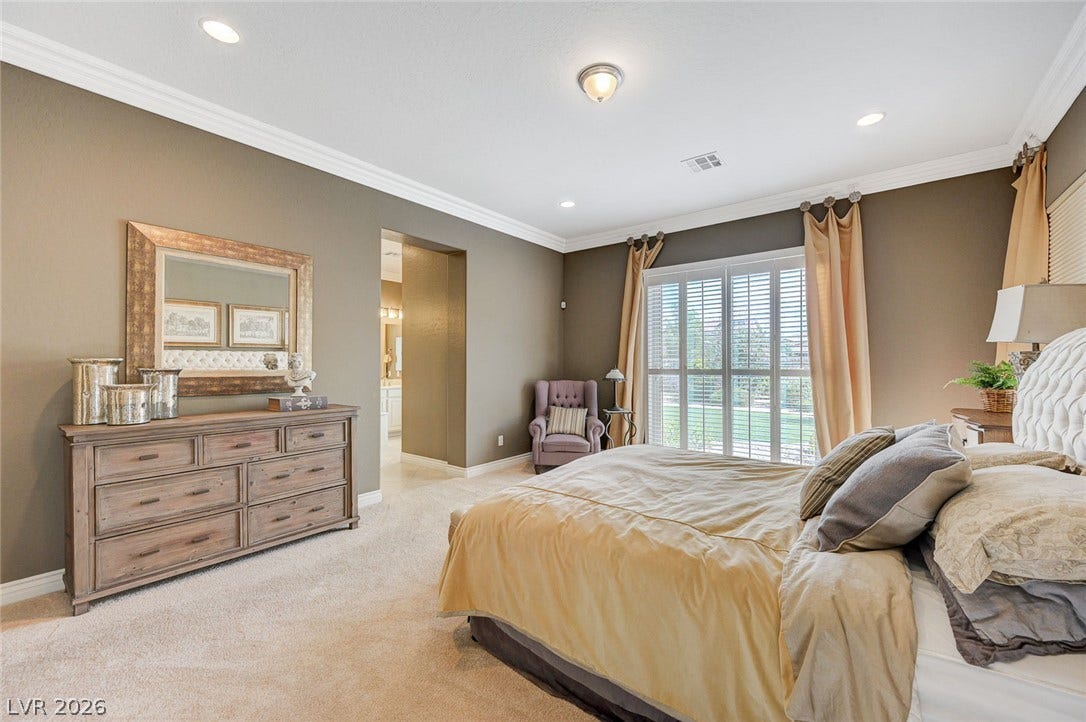 Plush carpeting and elegant crown molding elevate this serene primary bedroom retreat.