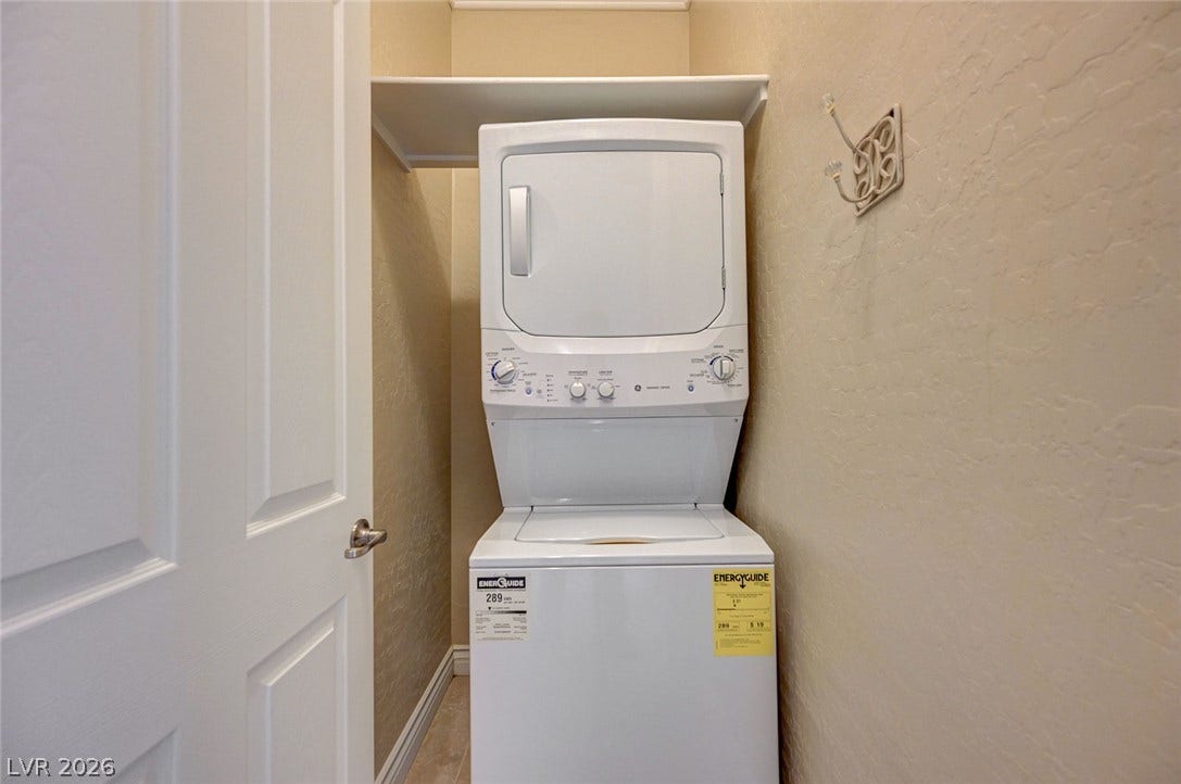 An efficient laundry nook features a stacked washer and dryer setup with built-in overhead shelving.