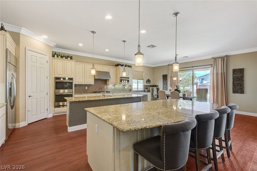 Polished granite countertops and warm wood floors define this expansive cooking and dining space.