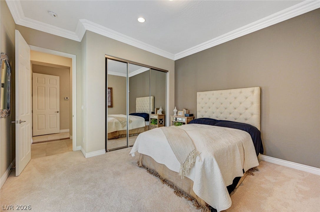 Thick crown molding and soft carpet frame this serene bedroom with mirrored closets.