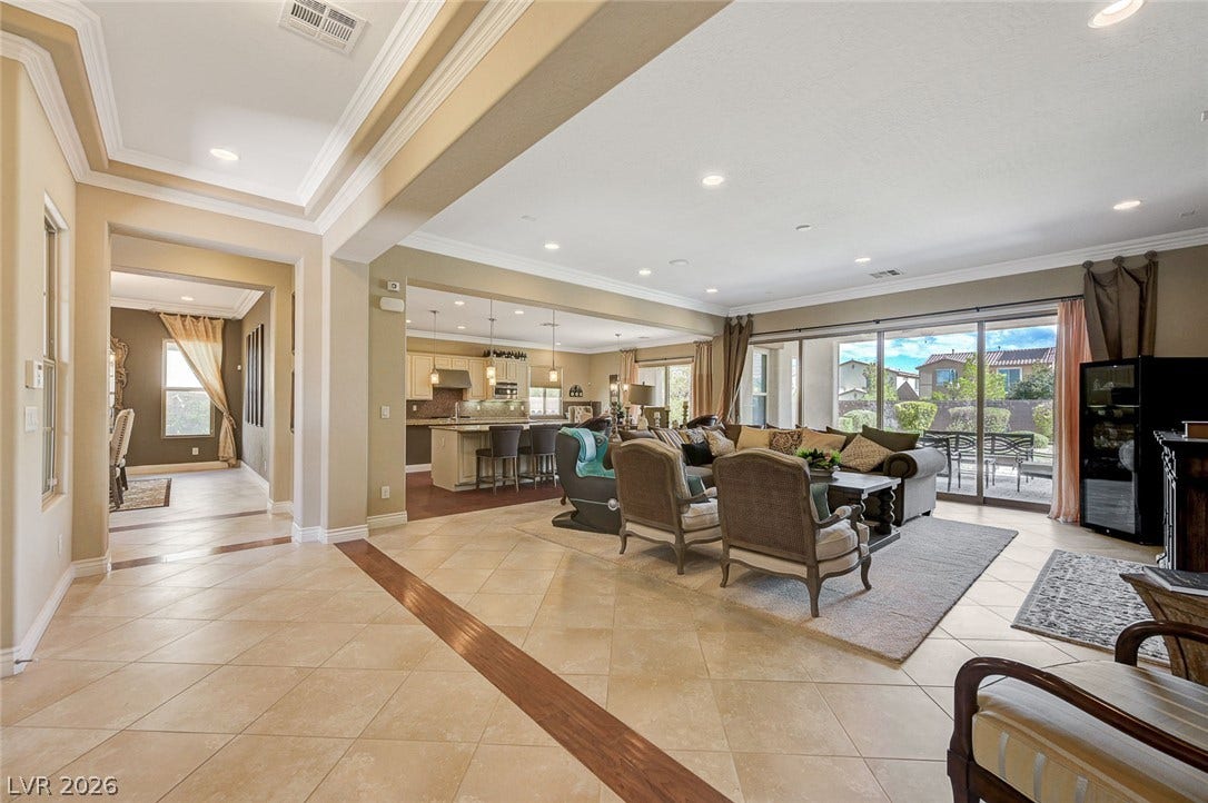 An open floorplan seamlessly connects the tiled living spaces to the adjacent kitchen.