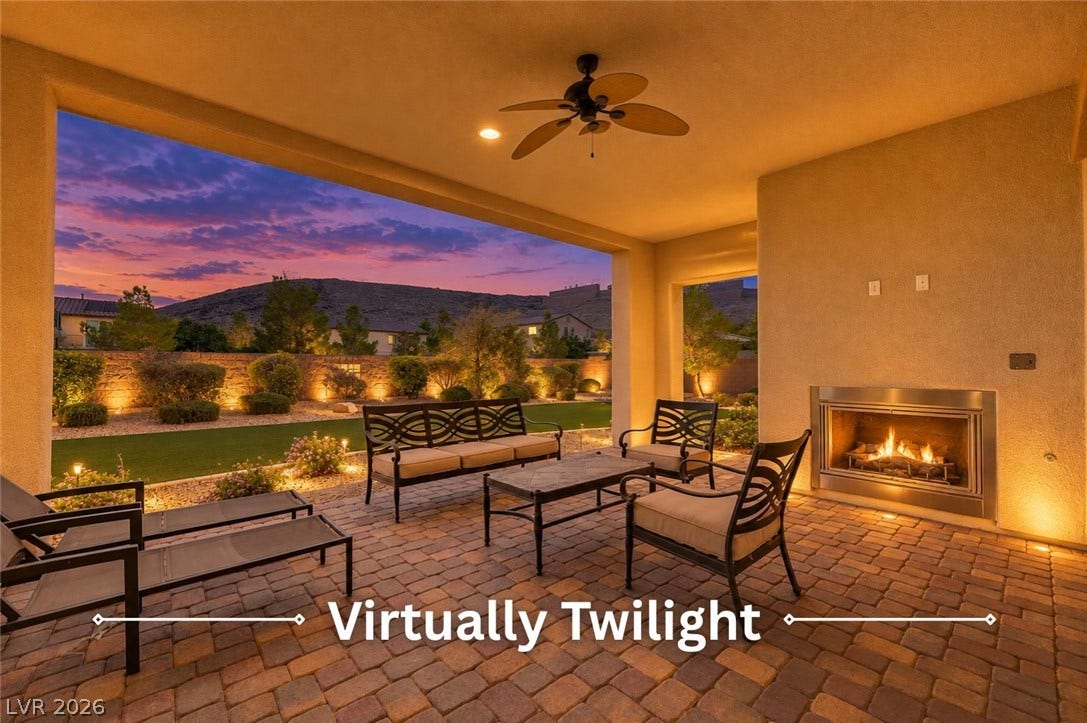 An inviting covered patio offers a built-in fireplace and serene mountain views at dusk.