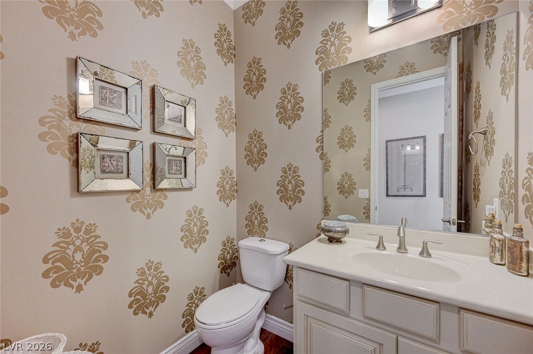 Elegant patterned walls and a classic vanity define this charming powder room.