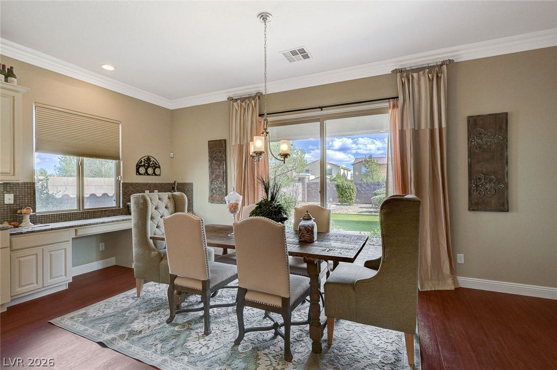 Rich wood flooring and classic crown molding frame this inviting formal dining room space.