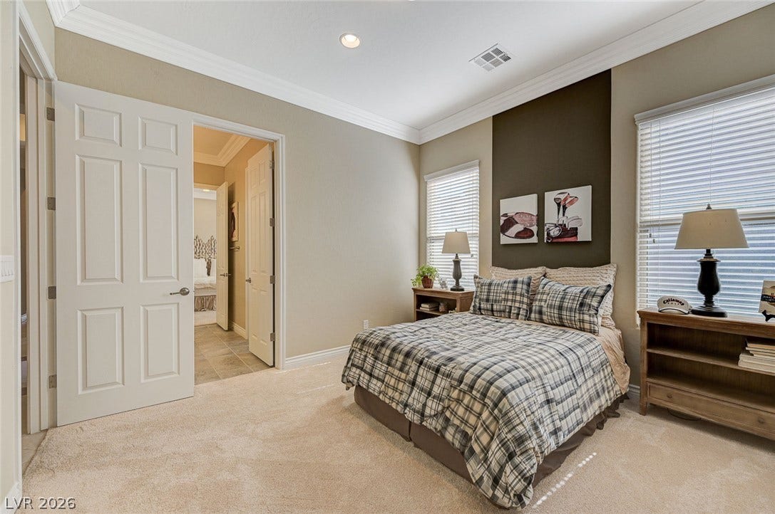 Elegant crown molding and plush carpeting define this comfortable secondary bedroom.