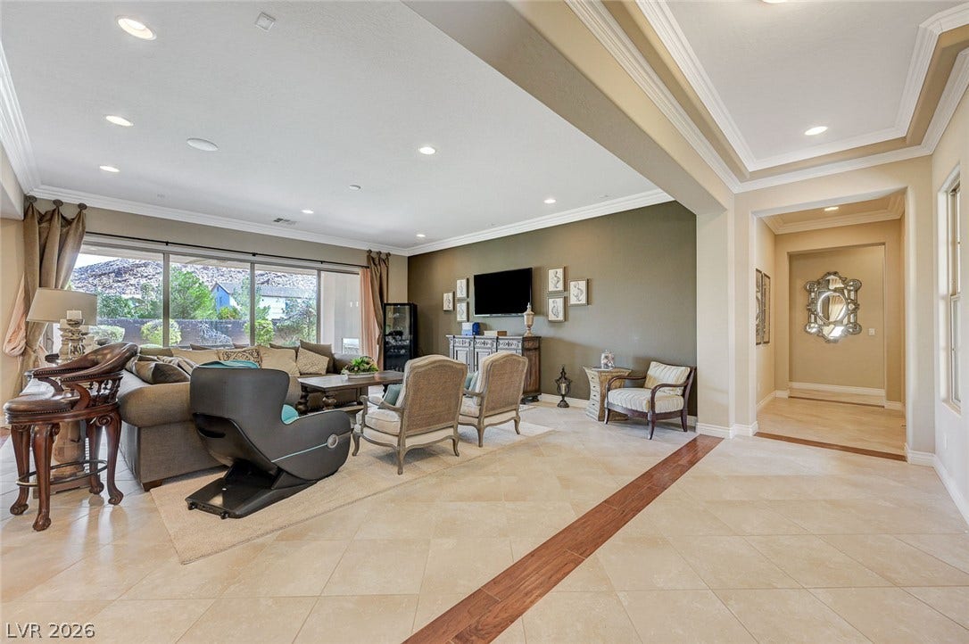 Polished tile flooring, detailed crown molding, and recessed lighting elevate this open principal living space.