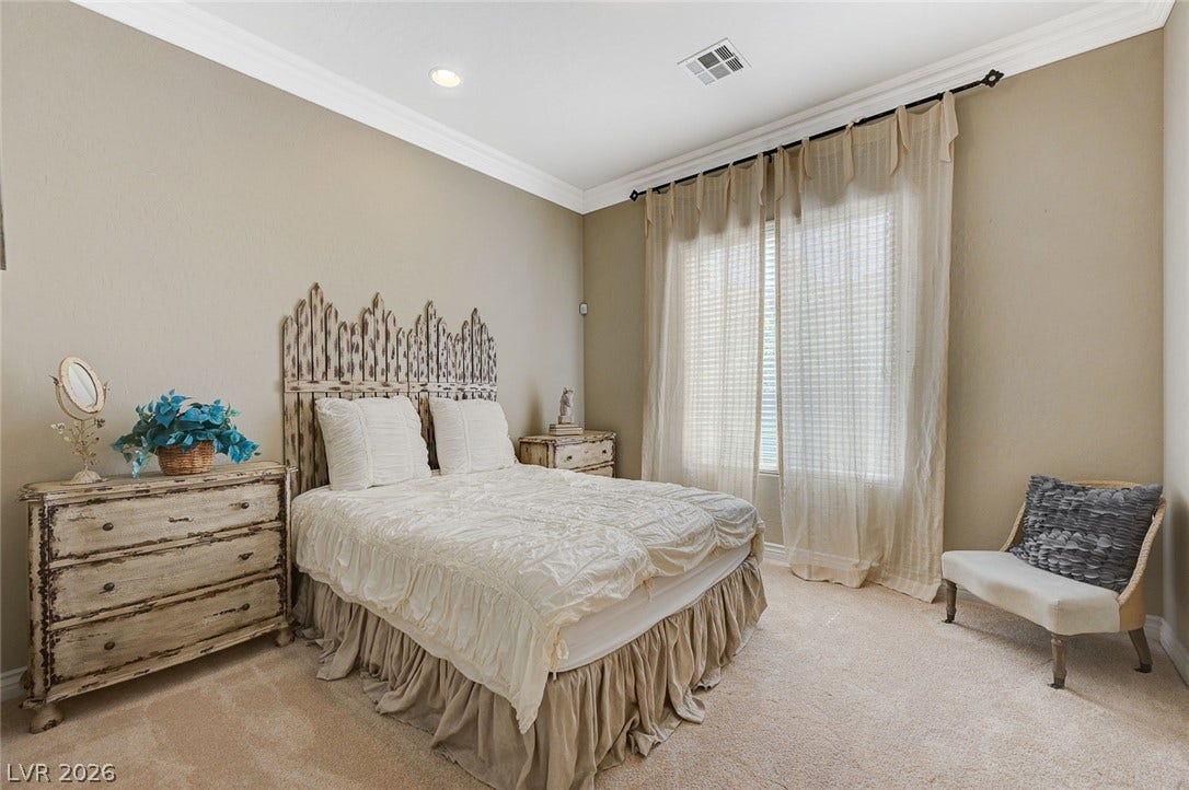 Crown molding and carpeted floors highlight this serene bedroom setting.