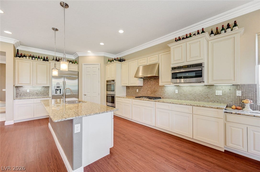 Gleaming wood floors anchor this expansive kitchen featuring classic white cabinetry and granite countertops.