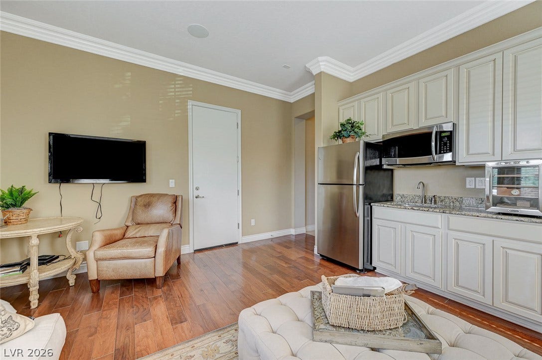 Rich hardwood flooring complements the classic crown molding in this versatile living space.