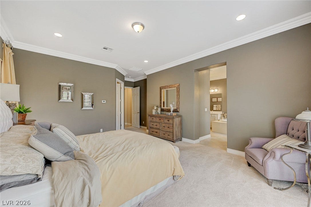 Elegant crown molding and plush carpeting define this spacious primary bedroom suite.
