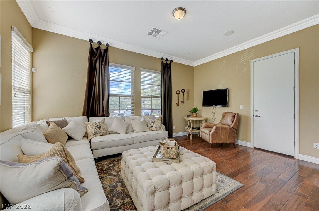 Rich wood flooring and elegant crown molding elevate this welcoming living space.