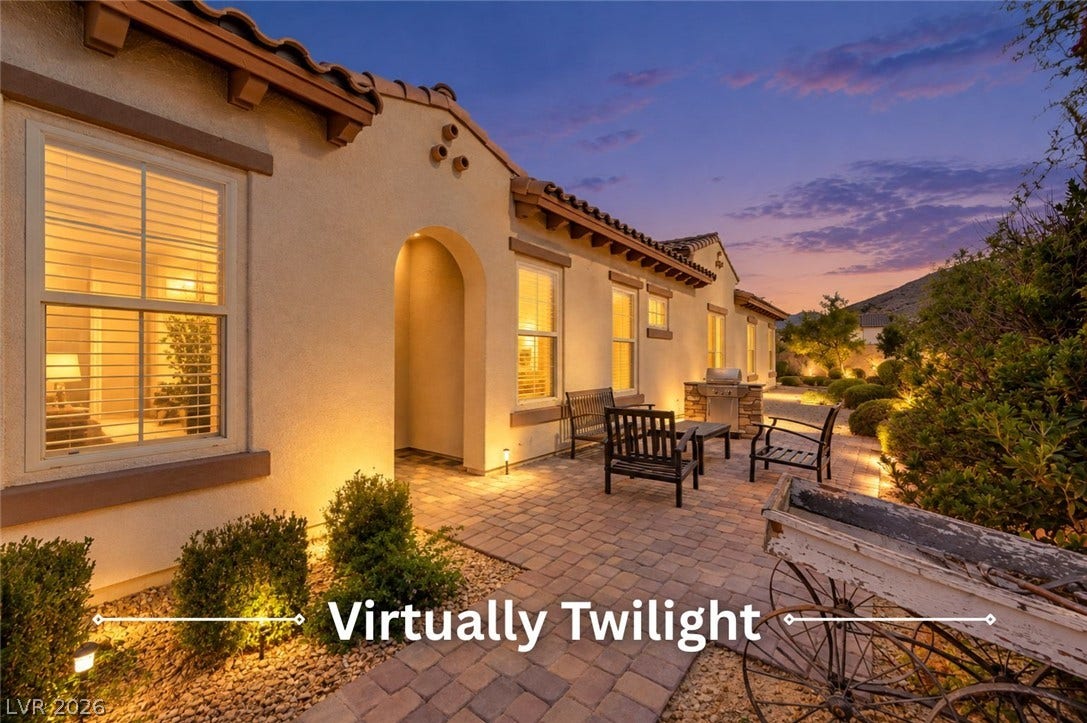 Inviting stone paved patio features warm exterior lighting set against a classic tile roofline.