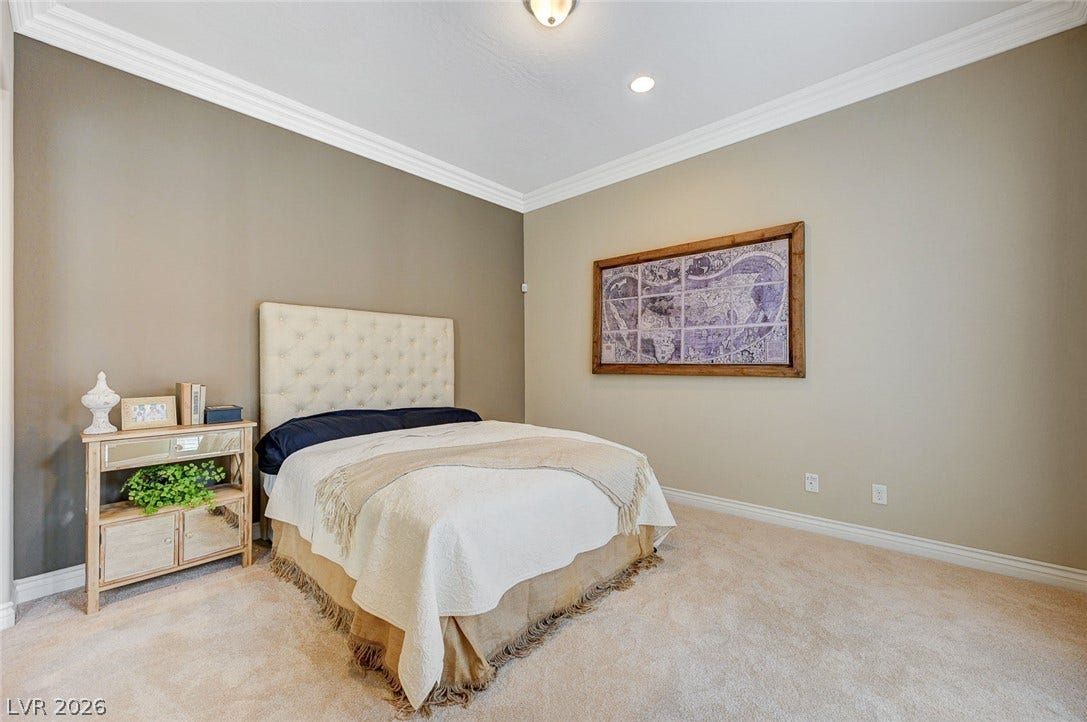 Crown molding highlights the high ceiling in this bedroom with wall-to-wall carpeting.