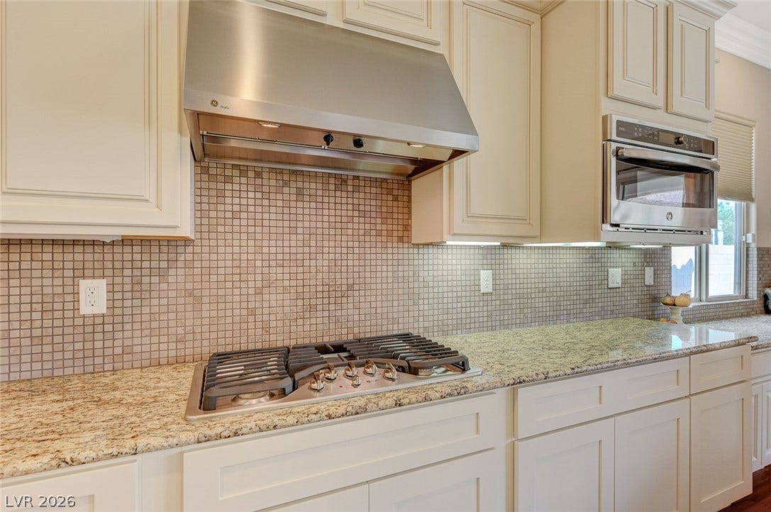 Polished granite countertops and classic cabinetry surround a premium gas cooktop and built-in microwave.