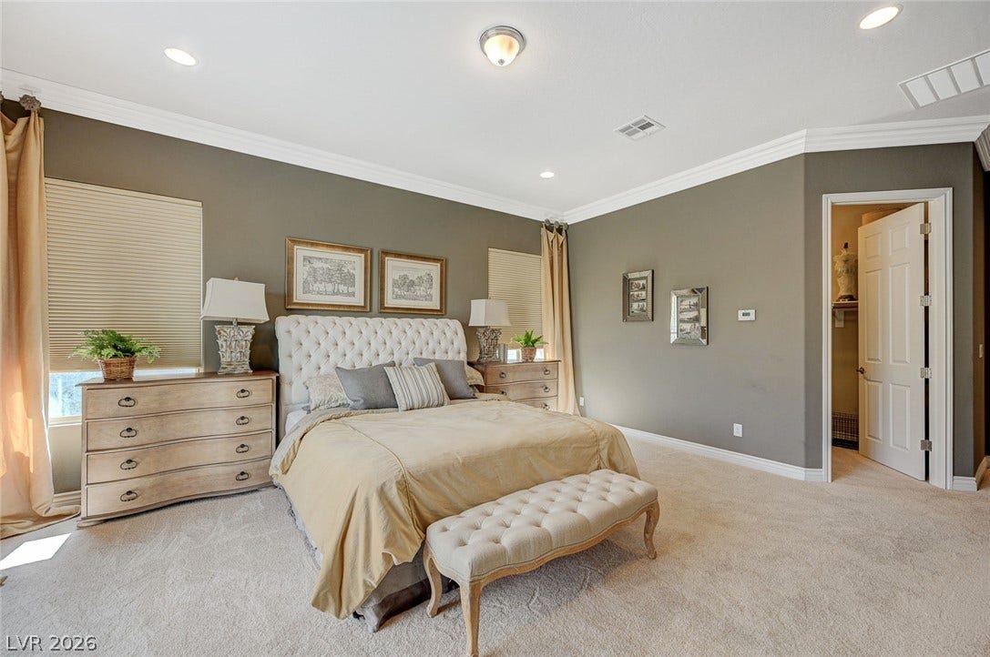 Crown molding frames this comfortable bedroom featuring soft carpeting and recessed lighting.