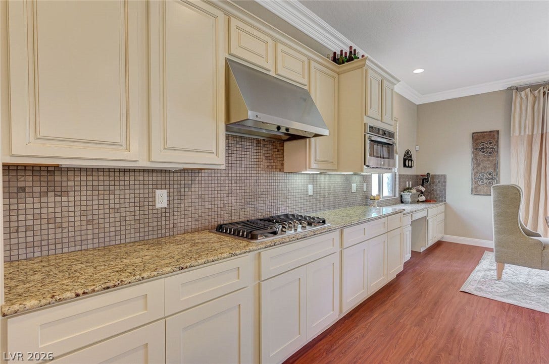 Elegant crown molding complements granite countertops and wood-look flooring in this spacious kitchen.