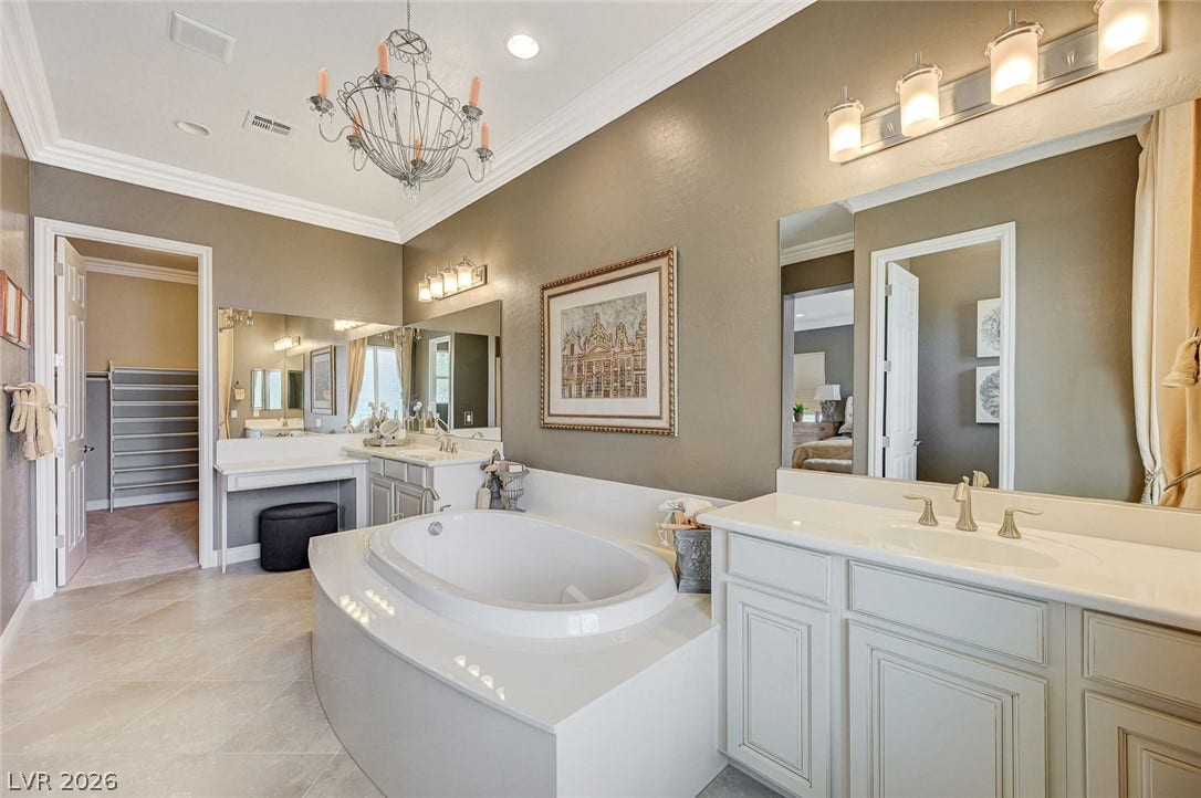 Elegant crown molding and tile flooring frame this bathroom featuring a large soaking tub.