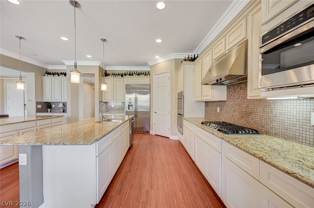 Polished granite countertops complement classic cabinetry and warm wood flooring in this culinary space.