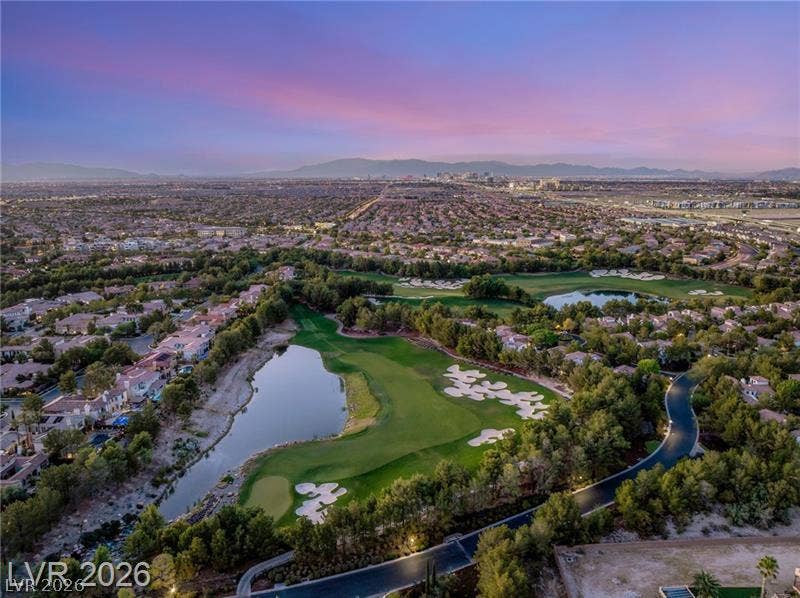 Lush fairways and sparkling lakes frame a vast neighborhood view beneath a twilight sky.