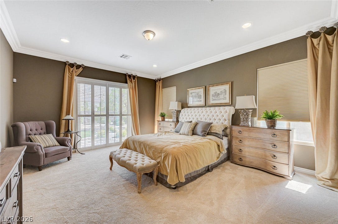 Thick crown molding and recessed lighting frame this comfortable bedroom retreat.