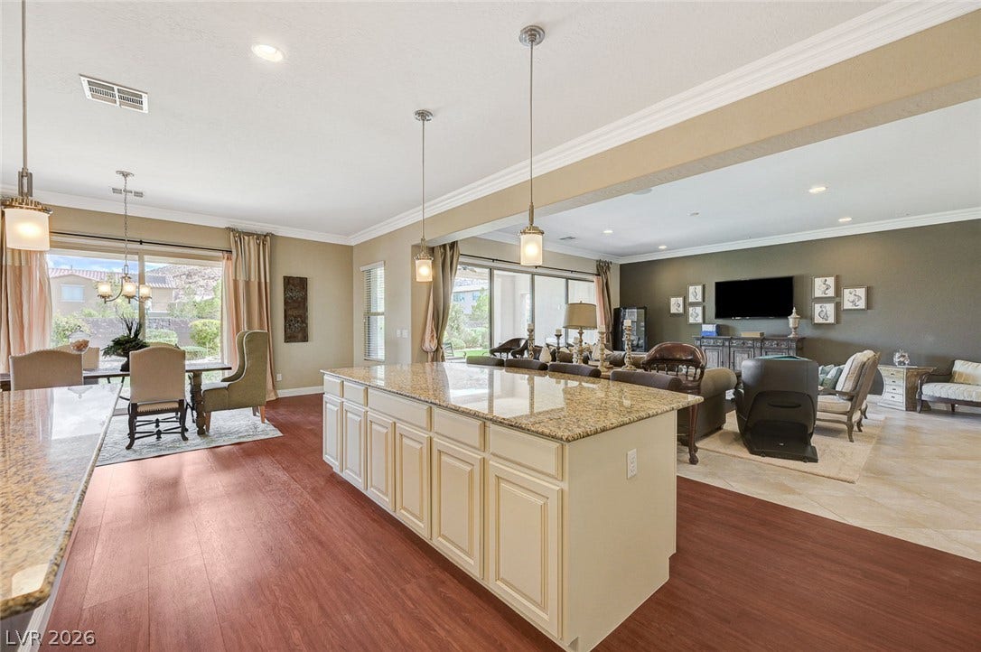 An open floorplan seamlessly connects the stone-countertop kitchen island to the adjoining living areas.